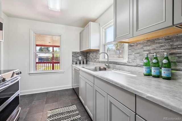 kitchen featuring a sink, light countertops, stainless steel appliances, baseboards, and decorative backsplash
