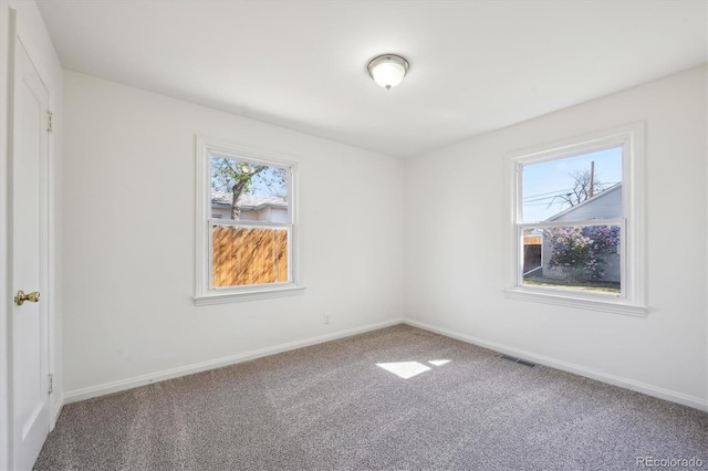 spare room with carpet floors, plenty of natural light, baseboards, and visible vents