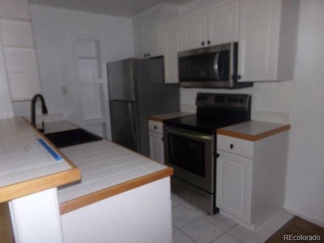 6705 S Field St Unit 802, Littleton, CO 80128 - kitchen featuring stainless steel appliances, a sink, white cabinetry, and light tile patterned floors