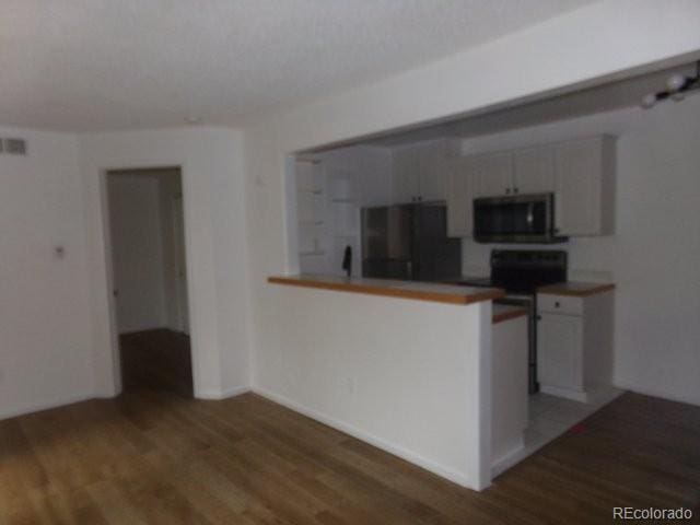 6705 S Field St Unit 802, Littleton, CO 80128 - kitchen featuring stainless steel microwave, refrigerator, light wood-type flooring, white cabinets, and a peninsula