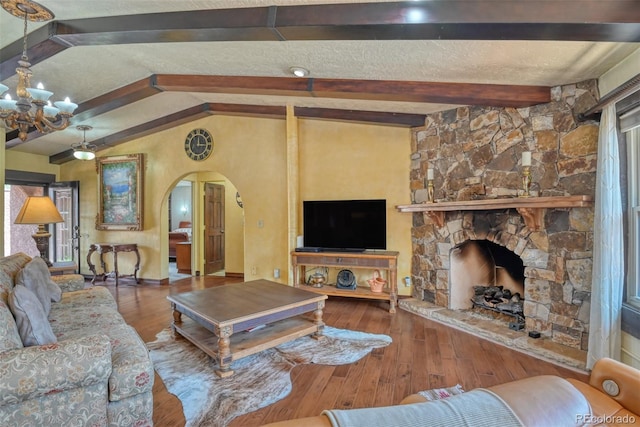 living room with hardwood / wood-style flooring, a fireplace, lofted ceiling with beams, and a chandelier