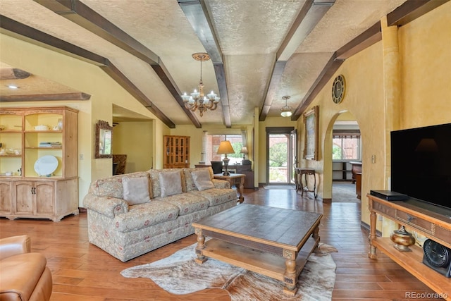 living room with beam ceiling, a chandelier, hardwood / wood-style floors, and a textured ceiling