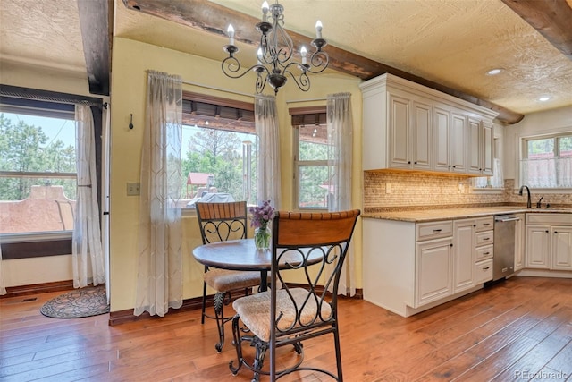 kitchen featuring tasteful backsplash, white cabinetry, light wood-type flooring, and a chandelier