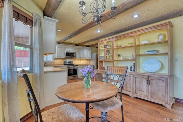 dining room with beamed ceiling and light hardwood / wood-style flooring