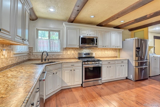 kitchen with appliances with stainless steel finishes, beam ceiling, sink, and white cabinets