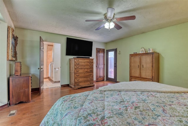 bedroom featuring ceiling fan, ensuite bathroom, a textured ceiling, and hardwood / wood-style flooring