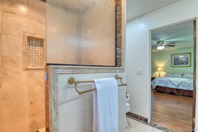 bathroom with tile patterned floors, ceiling fan, walk in shower, and toilet