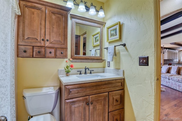 bathroom featuring hardwood / wood-style floors, vanity, beamed ceiling, and toilet