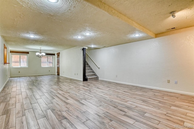 basement featuring a chandelier, a textured ceiling, and light hardwood / wood-style flooring