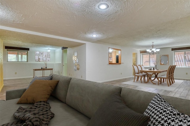 living room with hardwood / wood-style flooring, a textured ceiling, and an inviting chandelier