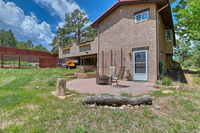 rear view of property featuring an outdoor fire pit, a patio area, and a lawn