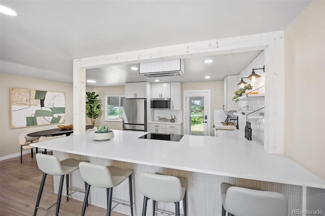 13249 W Jewell Pl, Lakewood, CO 80228 - kitchen featuring appliances with stainless steel finishes, a peninsula, white cabinetry, plenty of natural light, and recessed lighting