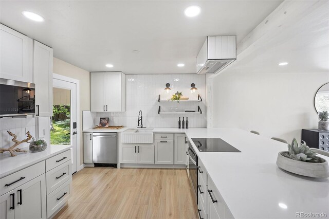 13249 W Jewell Pl, Lakewood, CO 80228 - kitchen featuring black appliances, decorative backsplash, light countertops, white cabinetry, and light wood finished floors