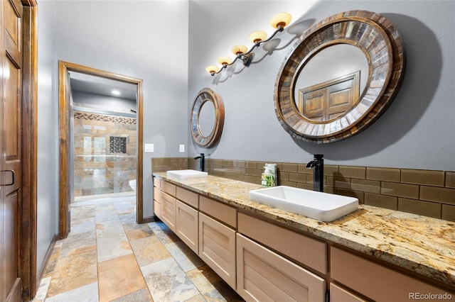 3900 Bogey Ct, Longmont, CO 80503 - bathroom featuring decorative backsplash, double vanity, toilet, and stone tile flooring