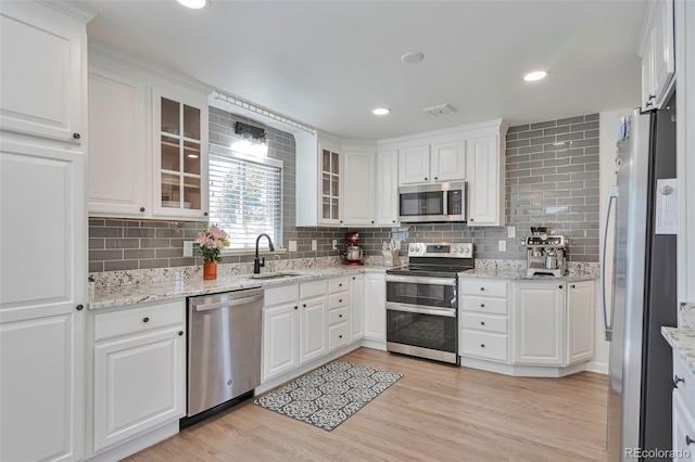 6179 S Bemis St, Littleton, CO 80120 - kitchen featuring stainless steel appliances, a sink, decorative backsplash, white cabinets, and light wood-style floors