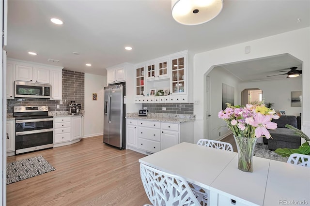 6179 S Bemis St, Littleton, CO 80120 - kitchen with appliances with stainless steel finishes, decorative backsplash, white cabinetry, light wood finished floors, and recessed lighting