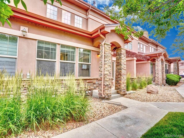 15501 E 112th Ave Unit 35B, Commerce City, CO 80022 - doorway to property featuring stucco siding and stone siding