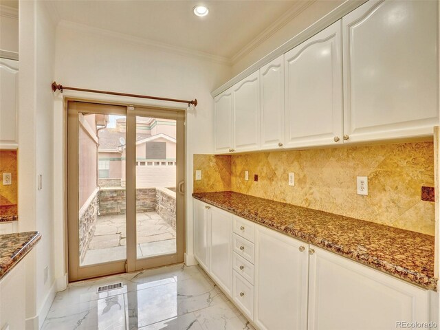 15501 E 112th Ave Unit 35B, Commerce City, CO 80022 - kitchen with light marble finish floors, dark stone counters, crown molding, white cabinets, and tasteful backsplash