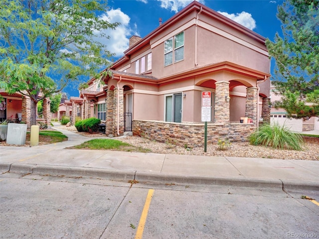 15501 E 112th Ave Unit 35B, Commerce City, CO 80022 - view of front of home with stucco siding, stone siding, and a chimney