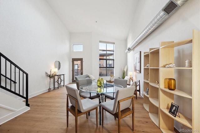 dining area with a towering ceiling and light hardwood / wood-style floors