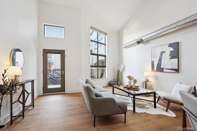 living area featuring a towering ceiling and light hardwood / wood-style floors