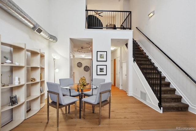 dining room with light hardwood / wood-style floors and a high ceiling