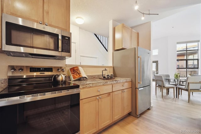 kitchen featuring appliances with stainless steel finishes, light brown cabinets, and light hardwood / wood-style flooring