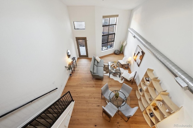 living room featuring a towering ceiling and light hardwood / wood-style flooring