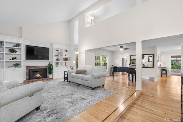 8535 E Otero Cir, Centennial, CO 80112 - living area with a high ceiling, light wood-style flooring, a brick fireplace, and a ceiling fan