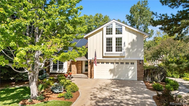 8535 E Otero Cir, Centennial, CO 80112 - view of front of house featuring brick siding, driveway, a garage, solar panels, and board and batten siding