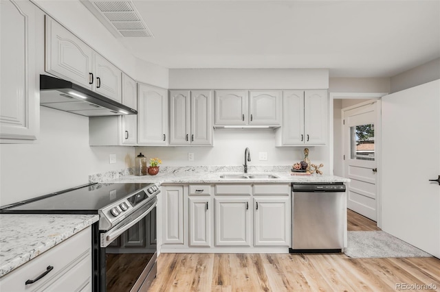 5947 W 65th Ave, Arvada, CO 80003 - kitchen with appliances with stainless steel finishes, under cabinet range hood, light wood-style floors, white cabinetry, and light stone counters