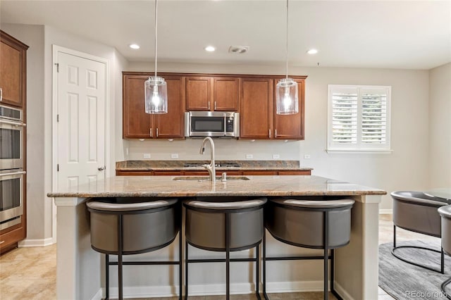 4545 Oxbow Dr, Brighton, CO 80601 - kitchen featuring stainless steel appliances, a breakfast bar, a sink, light stone countertops, and brown cabinets
