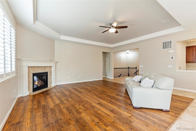 4545 Oxbow Dr, Brighton, CO 80601 - living room featuring a tray ceiling, a ceiling fan, wood finished floors, a tile fireplace, and crown molding