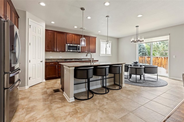4545 Oxbow Dr, Brighton, CO 80601 - kitchen featuring stainless steel appliances, recessed lighting, a kitchen bar, an island with sink, and decorative light fixtures