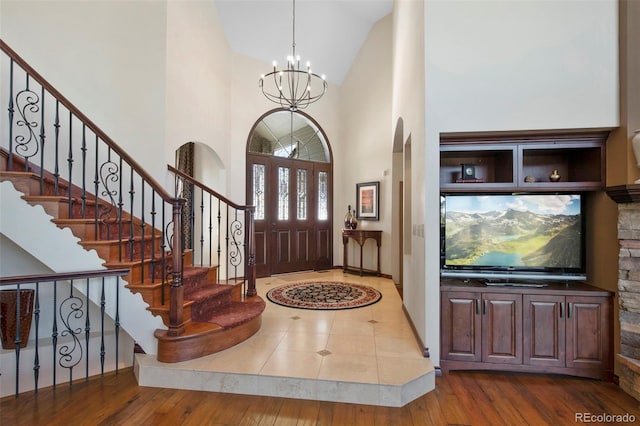 foyer with an inviting chandelier, a towering ceiling, and hardwood / wood-style flooring