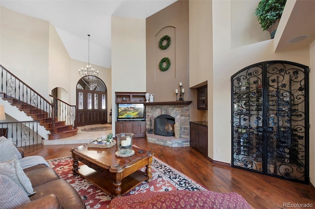 living room featuring a towering ceiling, a chandelier, a fireplace, and dark hardwood / wood-style floors