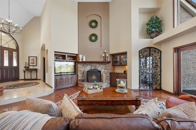 living room with a towering ceiling, a fireplace, a chandelier, and light wood-type flooring