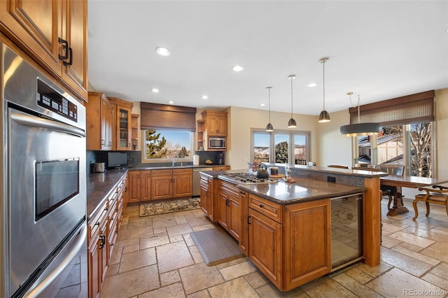 kitchen featuring wine cooler, a center island, hanging light fixtures, appliances with stainless steel finishes, and decorative backsplash