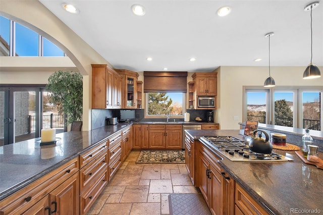 kitchen with stainless steel appliances, sink, backsplash, and decorative light fixtures