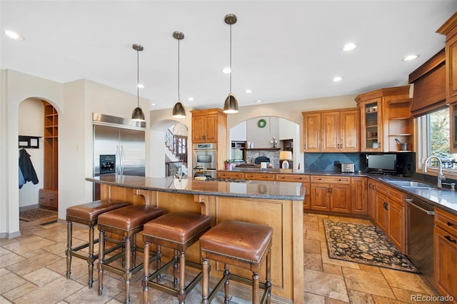 kitchen featuring tasteful backsplash, an island with sink, sink, a kitchen breakfast bar, and stainless steel appliances