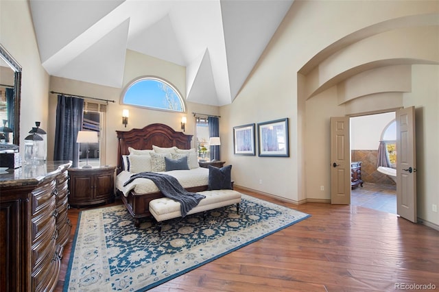 bedroom with wood-type flooring, high vaulted ceiling, and ensuite bathroom