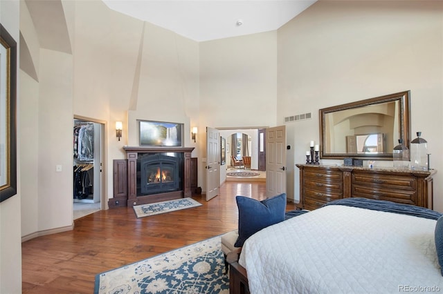 bedroom with a spacious closet, wood-type flooring, high vaulted ceiling, and a closet