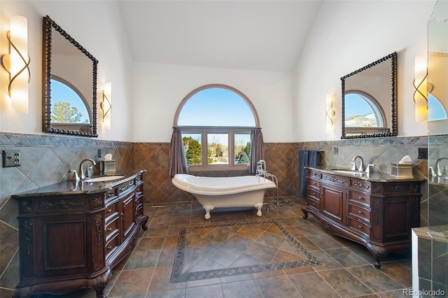 bathroom featuring vanity, lofted ceiling, tile walls, and a bathtub