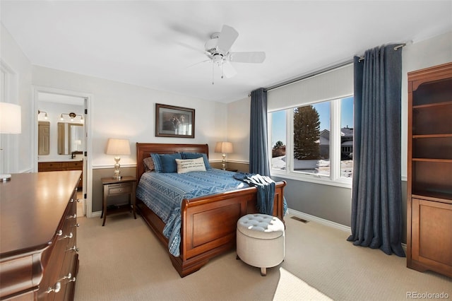 bedroom with ensuite bathroom, light carpet, and ceiling fan