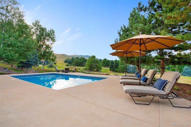 view of swimming pool with a mountain view and a patio area