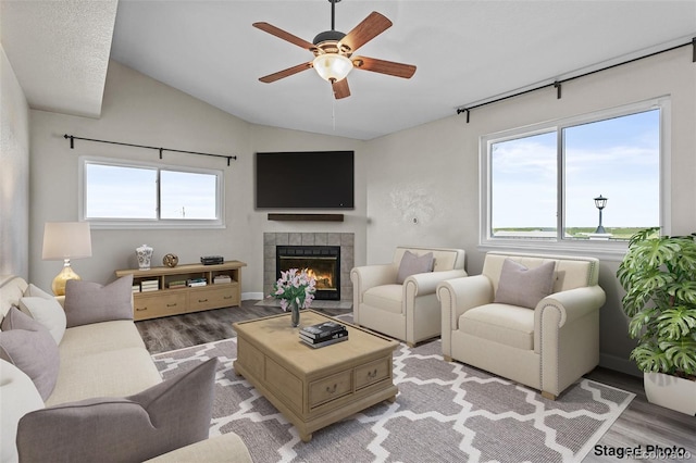 8979 Lariat Loop, Elizabeth, CO 80107 - living room featuring light wood-style floors, a ceiling fan, vaulted ceiling, and a tiled fireplace