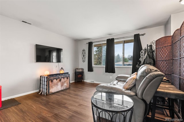 living room featuring wood finished floors, a wood stove, and baseboards