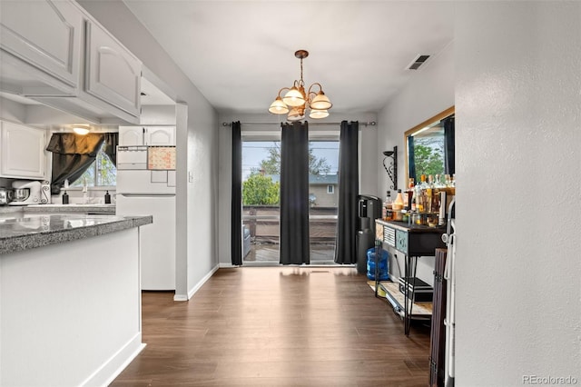 dining space with dark wood-type flooring, a chandelier, healthy amount of natural light, and baseboards