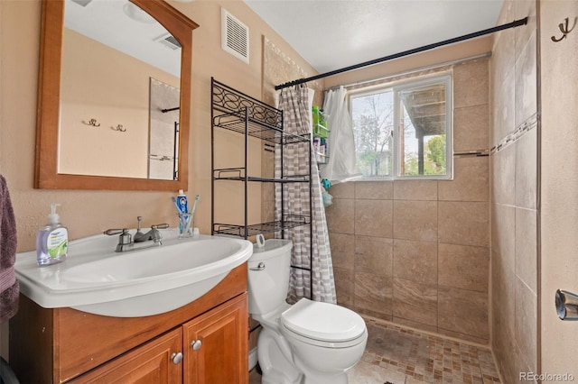 bathroom featuring tiled shower, toilet, and vanity