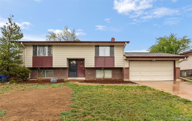 split foyer home featuring brick siding, an attached garage, driveway, a chimney, and a front yard